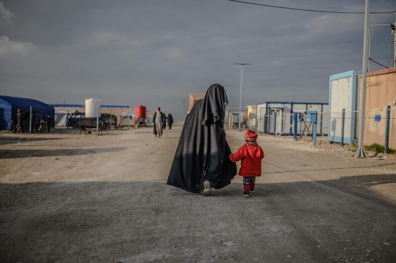 TOPSHOT - A veiled woman walks with her child at al-Hol camp in al-Hasakeh governorate in northeastern Syria on February 17, 2019.  / AFP / BULENT KILIC
