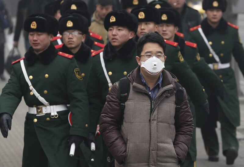 A citizen wears a protective mask against smog as a Chinese security unit for foreign embassies march behind him in Beijing on February 25. Rolex Dela Pena/EPA