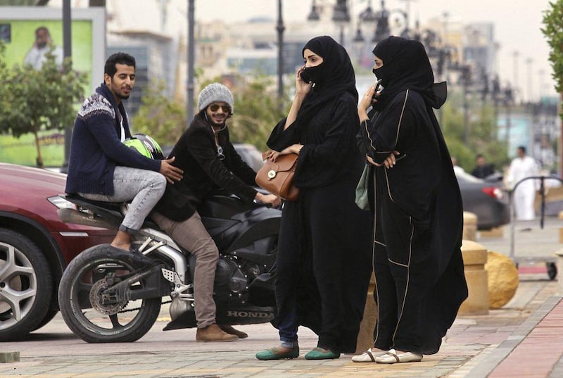 A woman speaks on the phone as men ride a motorcycle on a cloudy day in Riyadh. Faisal Al Nasser / Reuters