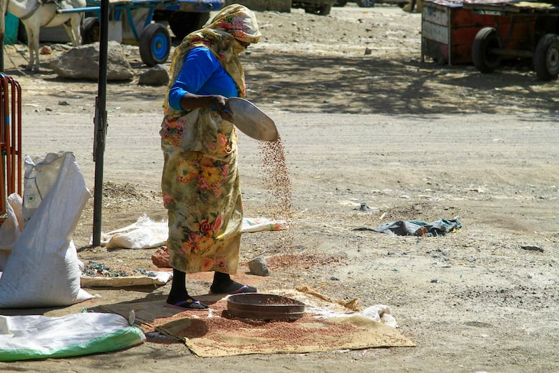 A woman sorts grains at a market in Gedaref, eastern Sudan, amid the ongoing civil war. AFP