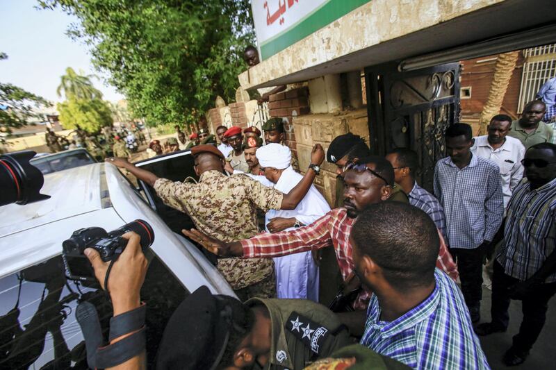 Sudan's ousted president Omar al-Bashir is escorted into a vehicle as he returns to prison following his appearance before prosecutors over charges of corruption and illegal possession of foreign currency, in the capital Khartoum on June 16, 2019. - Bashir was On June 16 seen in public for the first time since being ousted, as he was driven to the prosecutor's office. The former strongman, who ruled his northeast African nation with an iron fist for three decades, was toppled on April 11 after weeks of protests against his reign. (Photo by ASHRAF SHAZLY / AFP)