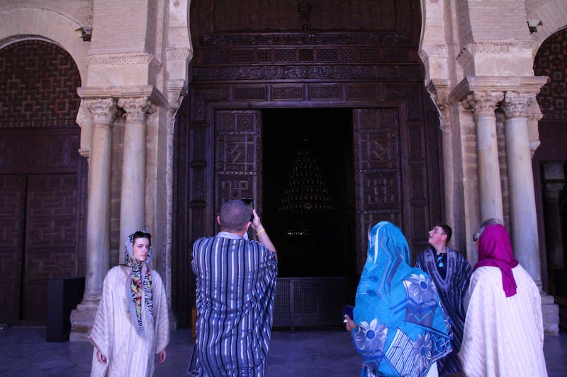 Tourists dressed in traditional Tunisian gowns visiting the holy Okba Grand Mosque in Kairouan