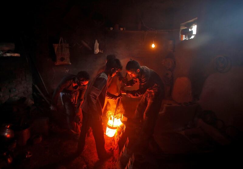 Workers pour melted copper in a mould to make accessories inside a workshop in Srinagar. Danish Ismail / Reuters