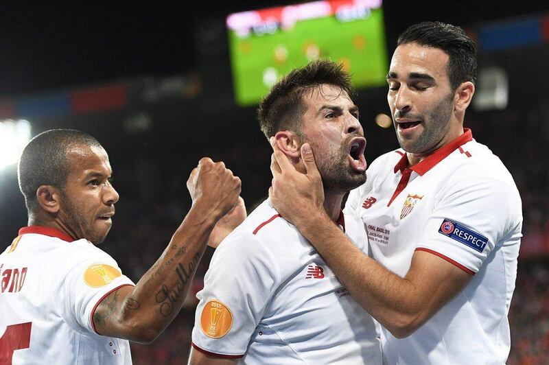 Coke, centre, celebrates with teammates Adil Rami, right, and Mariano Ferreira after scoring to put Sevilla 2-1 ahead. Jean-Christophe Bott / EPA