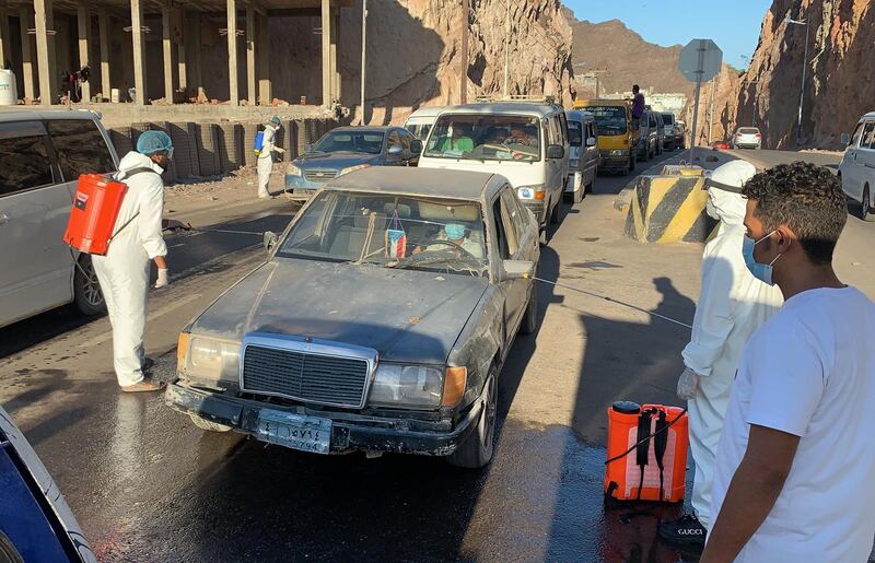 Workers of Yemen's separatist Southern Transitional Council (STC) disinfect vehicles at the entrance of Mualla, a district of the southern province of Aden, amid the COVID-19 pandemic on May 10, 2020.  / AFP / -
