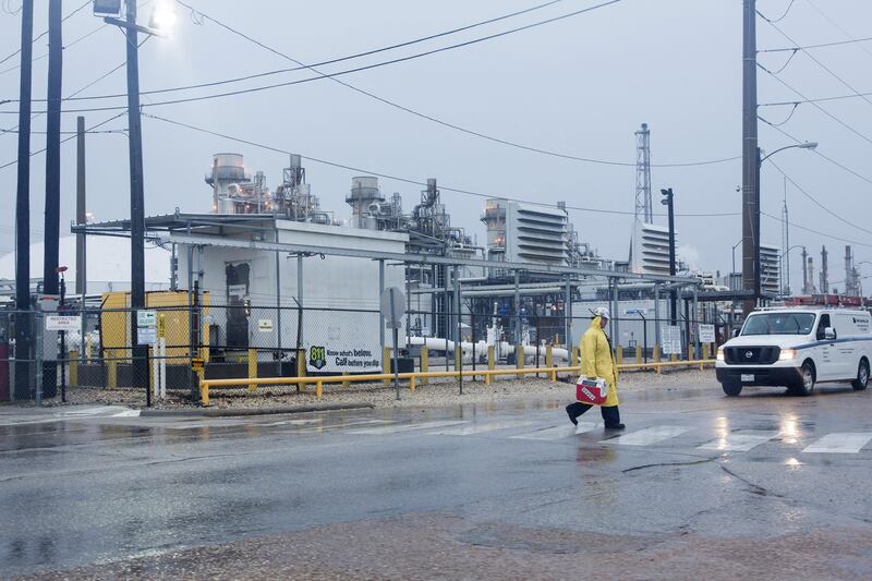 A worker wears rain gear while passing in front of the Marathon Petroleum Corp. refinery ahead of Hurricane Harvey in Texas City, Texas, U.S., on Friday, Aug. 25, 2017. Hurricane Harvey strengthened as it headed toward landfall in Texas, forecast to become the worst storm to strike the region in more than a decade. The price of gasoline rallied as it threatened to wreak havoc on the heart of America's energy sector. Photographer: F. Carter Smith/Bloomberg