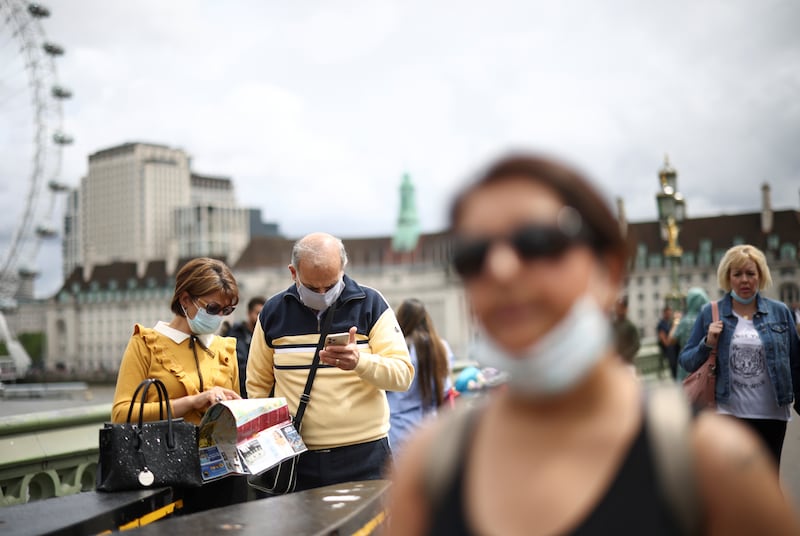 People wear masks while walking over Westminster Bridge in central London.