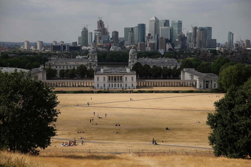 (FILES) In this file photo taken on July 23, 2018 The financial offices of banks, including JPMorgan Chase, Citi, HSBC, and other institutions in the financial district of Canary Wharf, are pictured on the horizon as visitors to Greenwich Park walk and play on the dry brown grass in east London on July 23, 2018. Britain's economy has grown at the fastest pace in nearly two years as strong exports and solid household spending offset slumping business investment, data showed on November 9, 2018 awaiting a Brexit deal. / AFP / Daniel LEAL-OLIVAS
