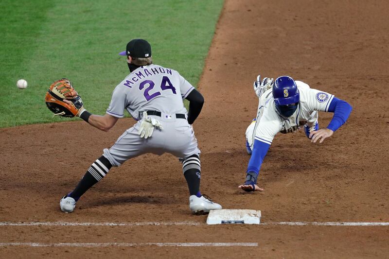 Seattle Mariners' Dylan Moore dives safely back to first base on a pick-off attempt as Colorado Rockies first baseman Ryan McMahon catches the ball in the eighth inning of a Major League Baseball game Sunday, August 9, in Seattle. AP