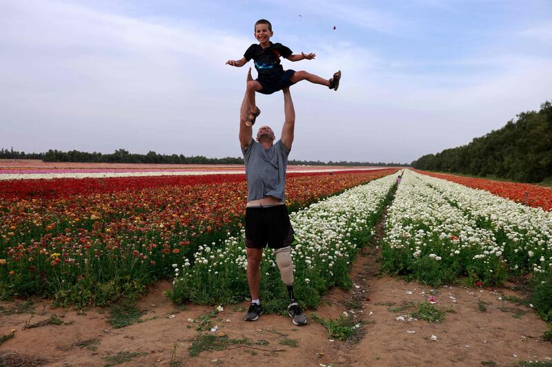 Adam Berdichevsky, Israeli wheelchair tennis champion, plays with his son at a ranunculus field at Nir Yitzhak. AFP