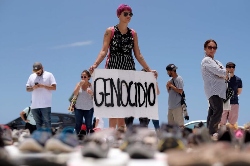 A woman holds a placard that reads in English "genocide" in front of hundreds of shoes that were displayed in memory of those killed by Hurricane Maria in front of the Puerto Rican Capitol, in San Juan. Ricardo Arduengo / AFP