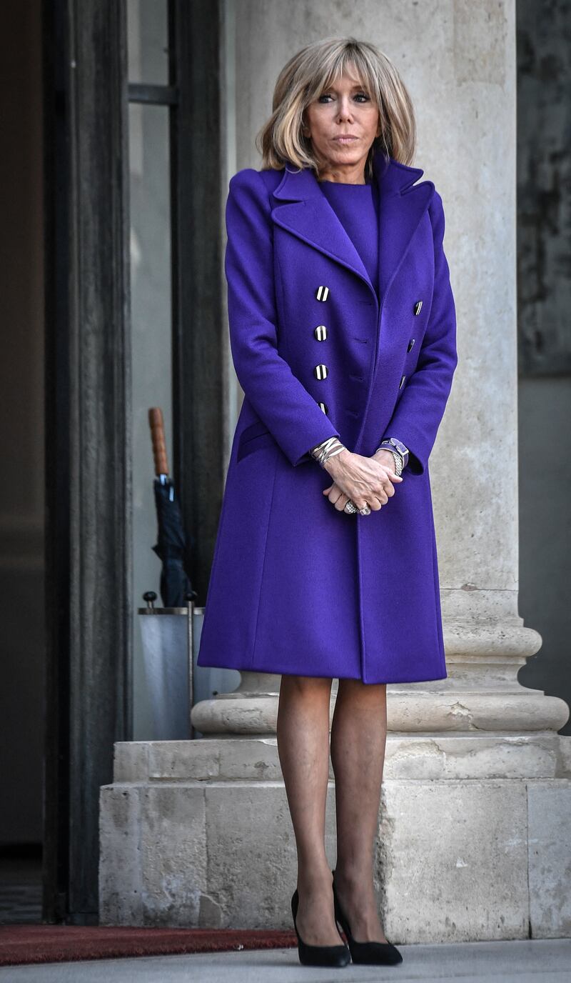 Brigitte, wearing a purple dress and matching coat, at the Elysee Palace on February 5, 2020. AFP