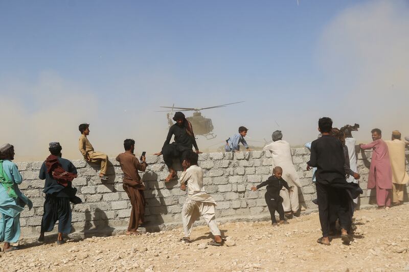 Residents gather as a rescue helicopter with medical supplies lands in a quake-hit Balochistan district, in south-west Pakistan. Reuters