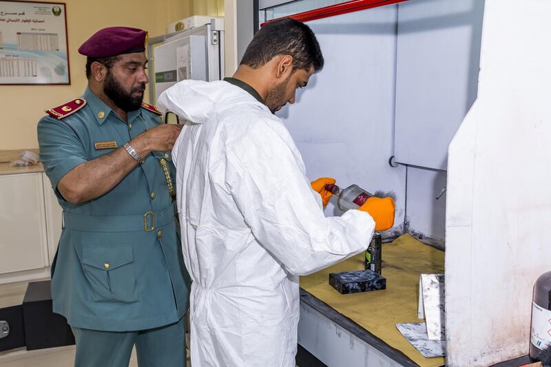 Ajman, UAE - September 05, 2017 - Mohd Hussain Waheedi of the Ajman Police Crime Scenes Investigative Unit prepares to collect fingerprints as Police Chief Abdalla Yousif Mohd S. Alawadi guides him - Navin Khianey for The National