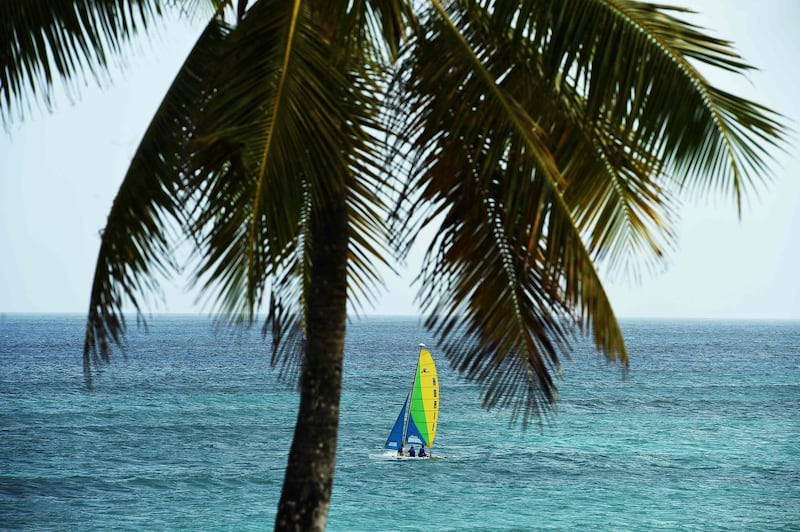 (FILES) In this file photo people sail on a boat near a beach in Bridgetown, Barbados on May 4, 2015.  Barbados has announced its intention to remove Queen Elizabeth II as head of state and become a republic by November next year, as the Caribbean island nation seeks to move fully beyond its colonial past.The decision was formalized in the so-called Throne Speech, delivered on behalf of Prime Minister Mia Mottley by the island's Governor-General Sandra Mason to mark the state opening of parliament on September 15, 2020. / AFP / Jewel SAMAD
