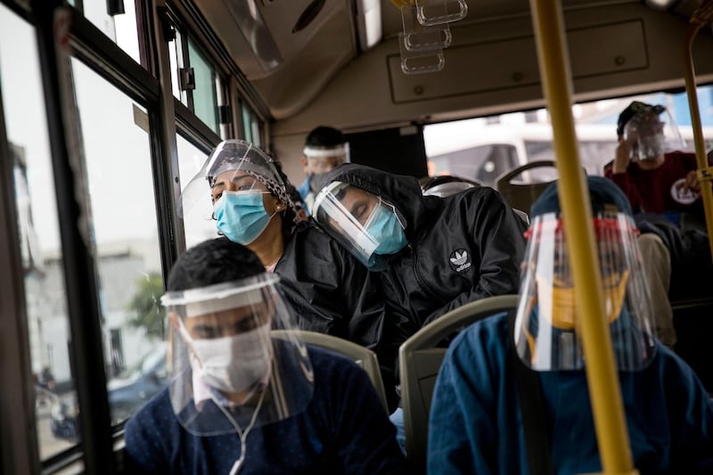 Commuters wearing protective face masks and face shields travel on a public bus in Lima, Peru. AP