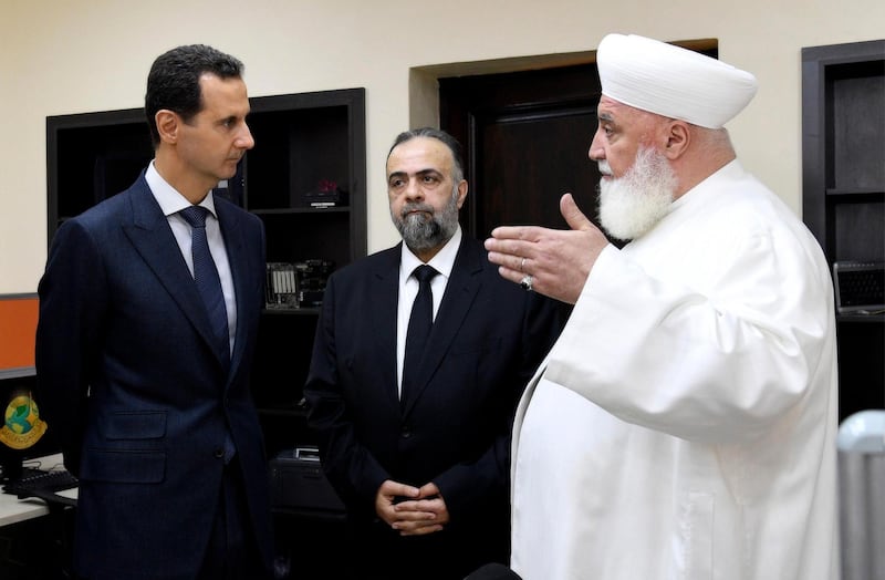 In this photo released on May, 20, 2019 by the Syrian official news agency SANA, shows Syrian President Bashar Assad, left, listens to Damascus Mufti Mohammed Adnan Afiouni, right, at an Islamic center, in Damascus, Syria.  Afiouni who played a key role in government deals with rebel fighters, was killed on Thursday Oct. 22, 2020 by an explosion in the town of Qudsaya, west of Damascus, Syria, when a roadside bomb exploded near him, according to state media and a government site. (SANA via AP)