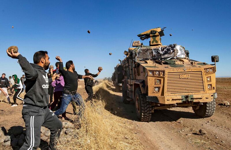 Kurdish demonstrators hurl rocks at a Turkish military vehicle, during a joint Turkish-Russian patrol near the town of Al Muabbadah in the northeastern part of Hassakah in 2019. AFP