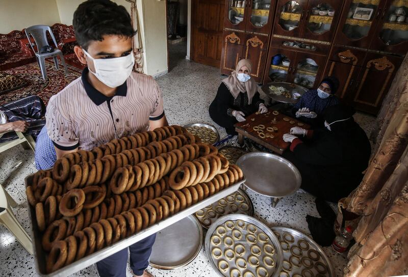 A Palestinian man, wearing protective face masks and gloves during the COVID-19 pandemic, carries a tray of baked traditional cookies in preparation for the upcoming Eid al-Fitr holiday which marks the end of the Islamic holy month of Ramadan, in the southern Gaza Strip city of Rafah.   AFP