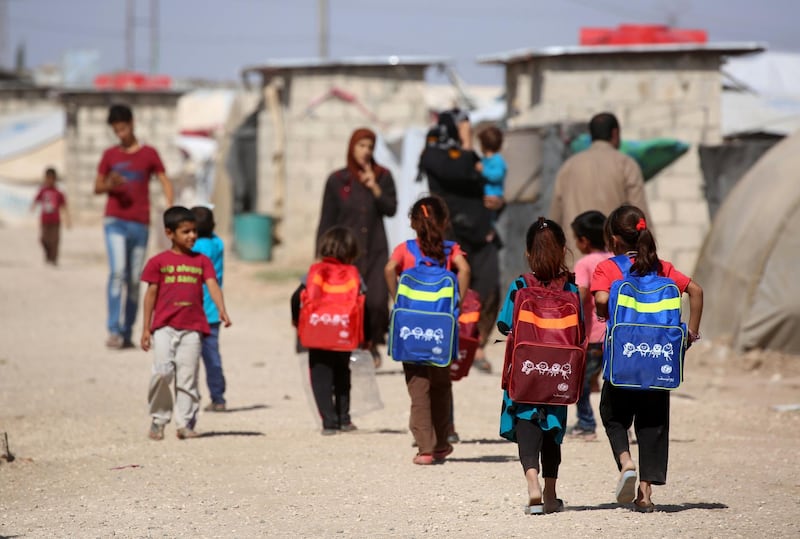 Children carry their schoolbags as they head to school on the first day of classes at a refugee camp housing Iraqi displaced families on September 28, 2016 in the Kurdish town of Derik (aka al-Malikiyah in Arabic), in the northeastern Hasakeh governorate, on the border with Turkey and Iraq. / AFP PHOTO / DELIL SOULEIMAN