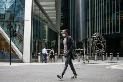 A pedestrian wearing a face mask crosses the street in the City of London. July 19 will mark the end of mask requirements in England. Bloomberg