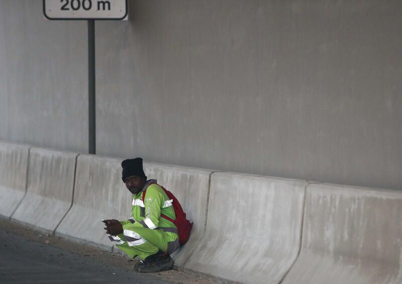A worker takes cover from the elements along the E11 motorway. 