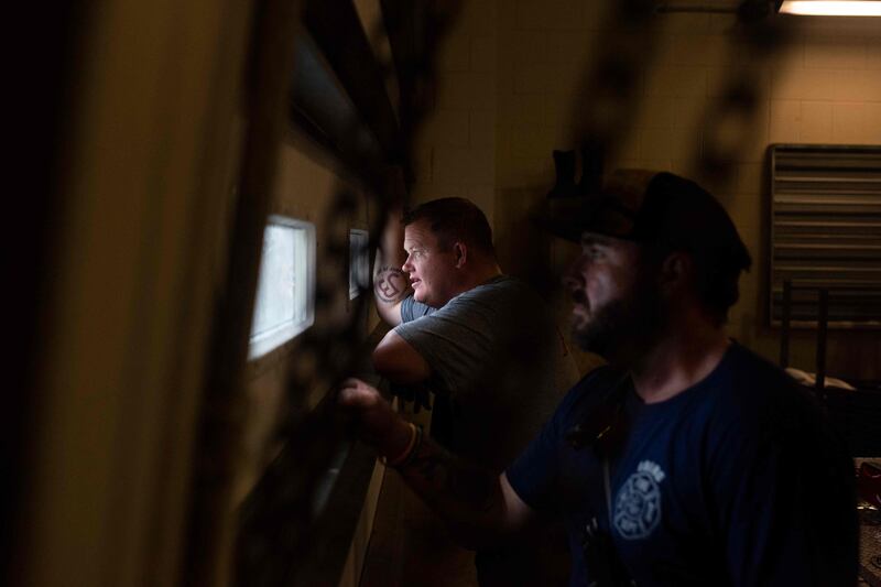 Firefighters look out the window from a shelter as hurricane Ida passes in Bourg. AFP