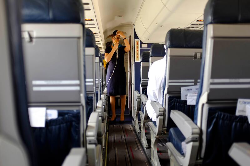 Abu Dhabi, United Arab Emirates - August 01 2013 - An airhostess demonstrates safety instructions on board the new Rotana Jet that operates as a commuter flight daily between Abu Dhabi and Dubai. Four National reporters raced from Abu Dhabi to Dubai using various modes of transport to see which vehicle took the least time between two cities.  (Razan Alzayani / The National) 