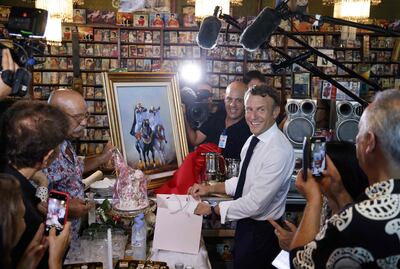 France's President Emmanuel Macron (C) receives a gift from Boualem Benhaoua (2ndL), owner of the disco Maghreb Shopin, mythical label of rai music, during his visit in Oran in Algeria in 2022. AFP
