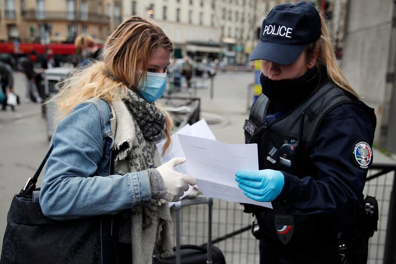 A French police officer checks a passenger's permission to leave home as she embarks a train at Montparnasse station in Paris, on March 21, 2020. AP Photo