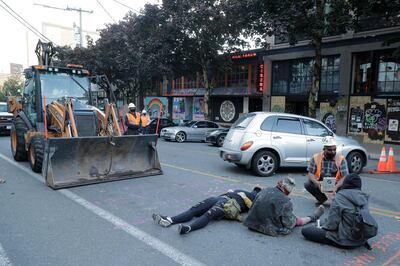 A Seattle Department of Transportation worker at right offers protesters lying down in the street first aid for a minor scrape after workers and heavy equipment from SDOT arrived at the the CHOP (Capitol Hill Occupied Protest) zone in Seattle, Friday, June 26, 2020, with the intention of removing barricades that had been set up in the area. Several blocks in the area have been occupied by protesters since Seattle Police pulled back from their East Precinct building following violent clashes with demonstrators earlier in the month. (AP Photo/Ted S. Warren)