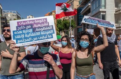 epa08483796 Anti-government protesters and supporters of Lebanese communist party carrying placards wave Lebanese flags as they march from the finance ministry to Ryad Al-Solh square in front the government palace during protests in Beirut, Lebanon, 13 June 2020. Anti-government protesters continue their protests against the economic condition, the collapsing of Lebanese currency and increasing prices.  EPA/NABIL MOUNZER