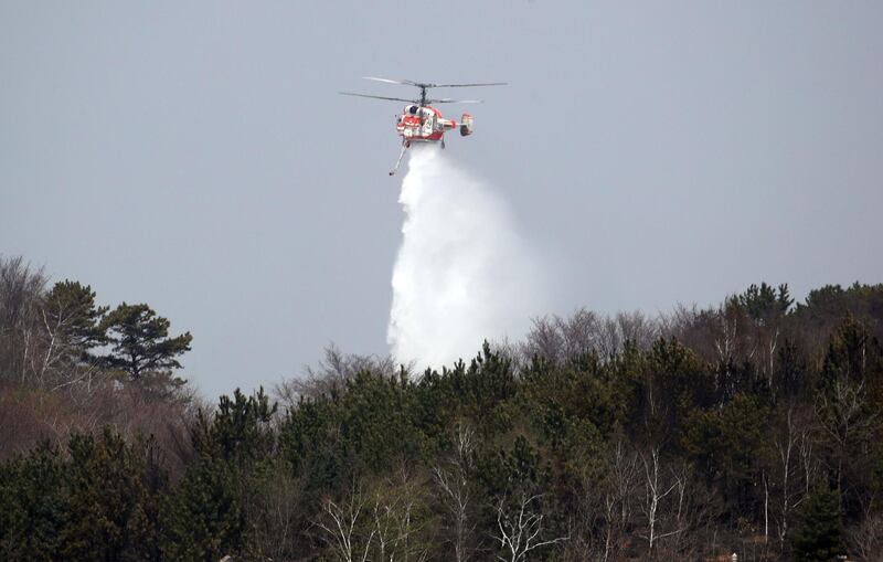 A firefighting helicopter helps to put out a forest fire. Yonhap / AFP