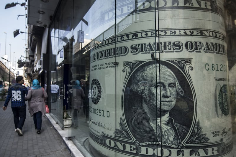 People walk past a currency exchange shop displaying a giant US dollar banknote in downtown Cairo. AFP