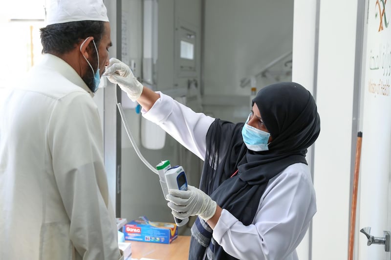 A Saudi nurse checks a patient's temperature at a mobile clinic catering for the residents of Ajyad Almasafi district in the holy city of Mecca, on April 7, 2020, which authorities have  sealed-off, along with other major cities, amid measures to curb the spread of COVID-19. Saudi Arabia's health minister warned of a huge spike in coronavirus cases of up to 200,000 within weeks, state media reported, a day after the kingdom extended the duration of daily curfews in multiple cities, including the capital, to 24 hours in a bid to limit the spread of the deadly virus. / AFP / BANDAR ALDANDANI
