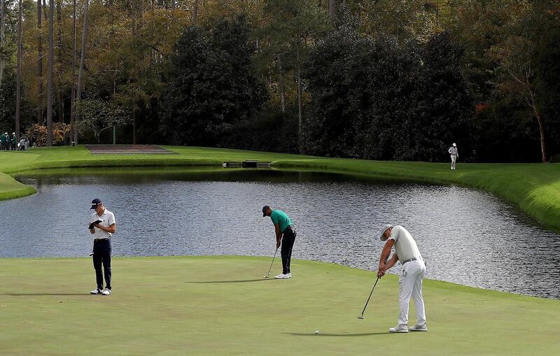 Tiger Woods and Bryson DeChambeau putt on the 16th green as Justin Thomas looks on during a practice round prior to the Masters. AFP