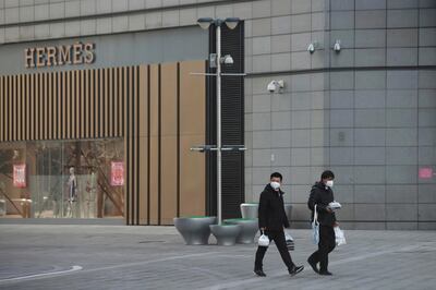 Men wearing face masks walk with takeaway food past a Hermes store at a shopping centre after the extended Lunar New Year holiday caused by the novel coronavirus outbreak, in Beijing's central business district, China February 10, 2020. REUTERS/Stringer   NO RESALES. NO ARCHIVES.