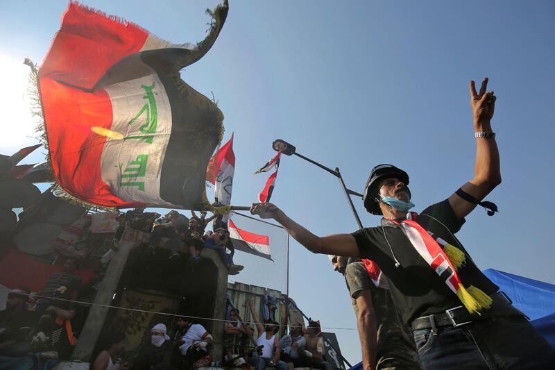 A demonstrator waving a national flag flashes the victory sign near al-Jumhuriya bridge. AFP