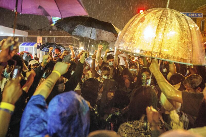 Protesters gather under the rain near the spot where George Floyd died while in custody of the Minneapolis Police, on May 26, 2020 in Minneapolis, Minnesota. - A video of a handcuffed black man dying while a Minneapolis officer knelt on his neck for more than five minutes sparked a fresh furor in the US over police treatment of African Americans Tuesday. Minneapolis Mayor Jacob Frey fired four police officers following the death in custody of George Floyd on Monday as the suspect was pressed shirtless onto a Minneapolis street, one officer's knee on his neck. (Photo by Kerem Yucel / AFP)