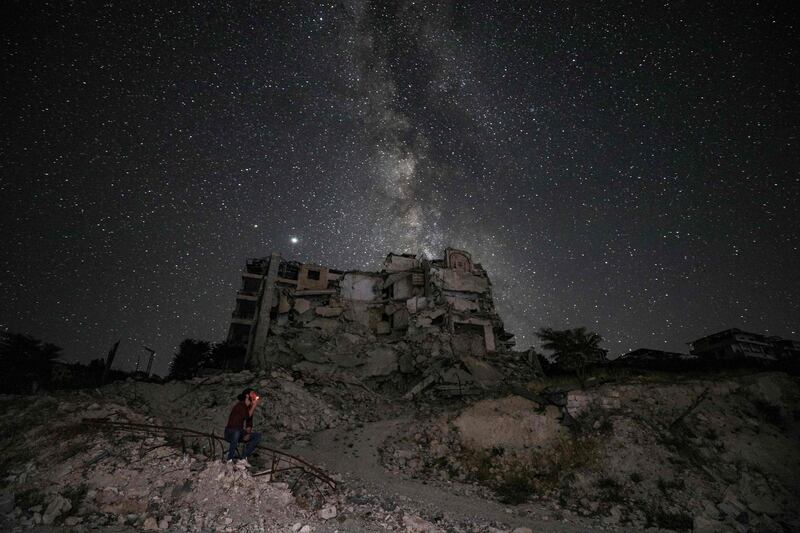 This long-exposure picture taken early shows a man smoking past buildings destroyed by prior bombardment in the town of Ariha in Syria's rebel-held northwestern Idlib province, as the Milky Way galaxy is seen in the night sky above. AFP