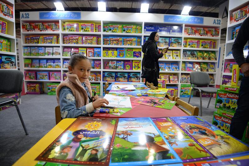 An Egyptian girl checks a book at the children's section at the grounds of the 50th Cairo International Book Fair which was opened in the New Cairo suburb of the Egyptian capital on January 23, 2019. / AFP / MOHAMED EL-SHAHED                   
