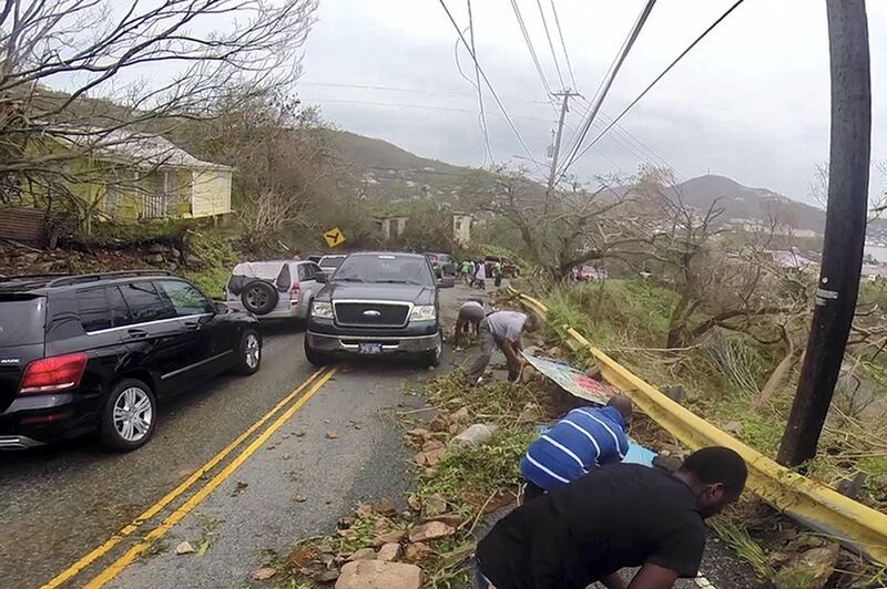 In this image made from video, motorists remove debris caused by Hurricane Irma from the road in St. Thomas, U.S. Virgin Islands, Thursday, Sept. 7, 2017. Hurricane Irma weakened slightly Thursday with sustained winds of 175 mph, according to the National Hurricane Center. The storm boasted 185 mph winds for a more than 24-hour period, making it the strongest storm ever recorded in the Atlantic Ocean. The storm was expected to arrive in Cuba by Friday. It could hit the Florida mainland by late Saturday, according to hurricane center models. (AP Photo/Ian Brown)