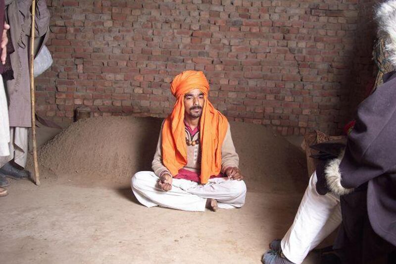 Safdar Ali sits in front of the grave in which he spent 41 hours. His faith healer told him the burial would stop his 'possession'.