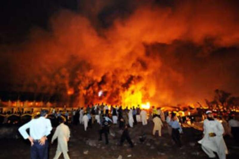 Pakistani policemen and onlookers gather as a cloud of smoke billows from the burning Marriott hotel following a powerful bomb blast in Islamabad on Sept 20 2008.