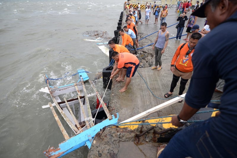 Members of the Philippine Coast Guard haul in the wreckage of boat on Sunday, which capsized off the coast of Guimaras Island a day earlier, in Visayas Region. According to reports, at least two dozen 26 passengers were killed after three motorised boats capsized  amid bad weather conditions. Leo Solinap / EPA