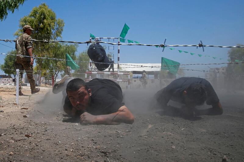 Young Palestinians crawl under a barbed wire during a military-style exercise at a Hamas-run summer camp in Gaza City. Reuters