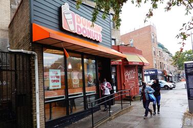 People walk past a Dunkin' store in New York City. The Dunkin’ Brands, the parent company of the Dunkin’ and Baskin Robbins chains, agreed to sell itself to Inspire Brand, a private equity-backed company. AFP