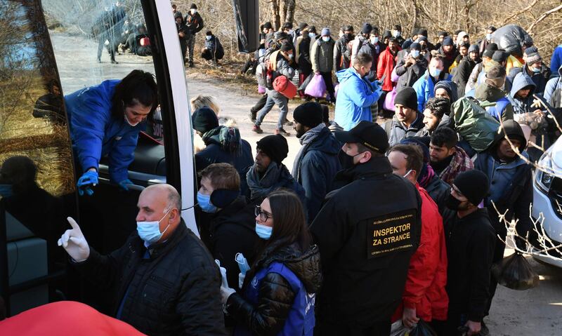 Migrants board a bus as they leave the camp. AFP
