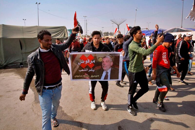 Protesters chant slogans while holding a poster of prime minister-designate Mohammed Allawi with the slogan, "Rejected by the people," during a demonstration in Najaf, Iraq. AP Photo