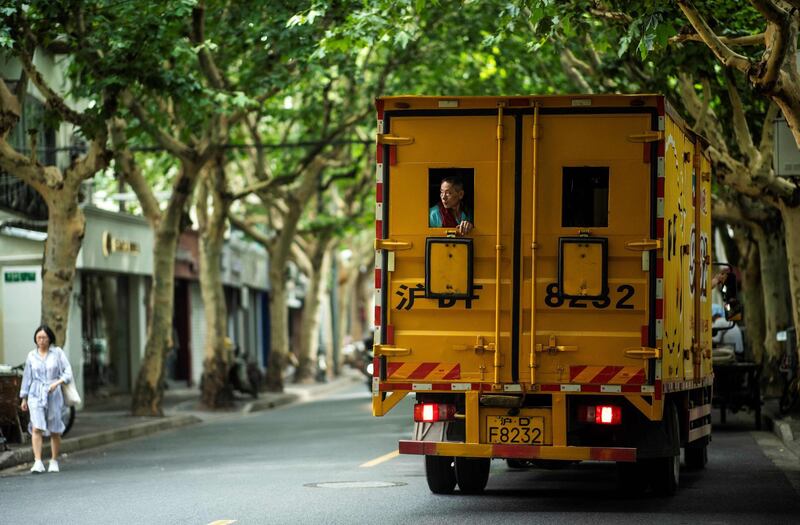 A worker looks out of the window of a moving company truck as it drives through the streets of the former French Concession in Shanghai. Johannes Eisele/AFP